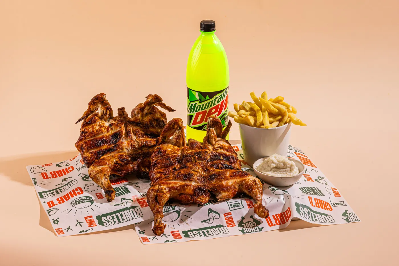 Two charcoal chickens with chips, salad, garlic sauce and a drink on Char’d paper